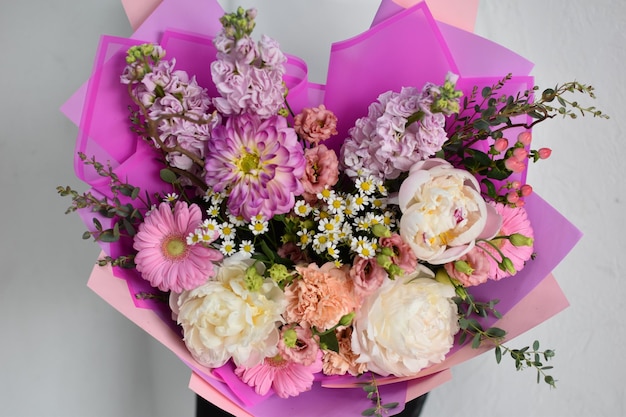 Femme avec de belles fleurs dans les mains à l'intérieur fond bouquet de fleurs pour fleuriste