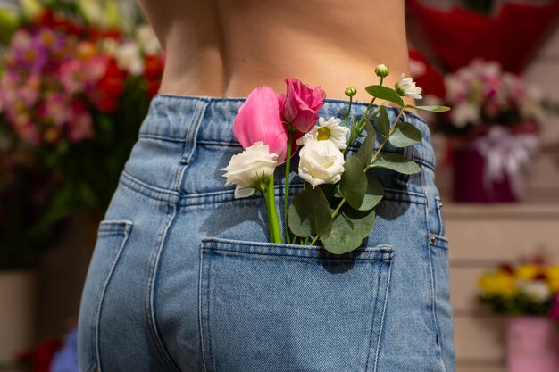 Femme avec de belles fleurs tendres dans la poche arrière d'un jean Femme poignarde dos à la caméra Un petit bouquet de fleurs des champs dans une poche arrière