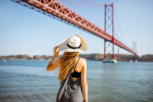 Femme bénéficiant d'une belle vue paysage sur le célèbre pont de fer debout près de la rivière à Lisbonne, Portugal