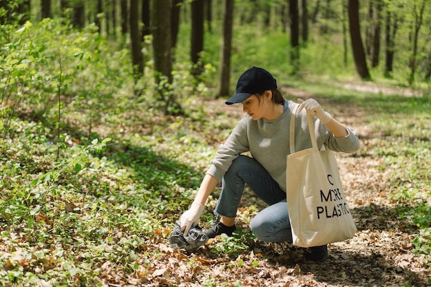 Une femme bénévole est nettoyée dans la forêt Une femme ramasse du plastique