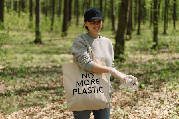 Une femme bénévole est nettoyée dans la forêt Une femme ramasse du plastique