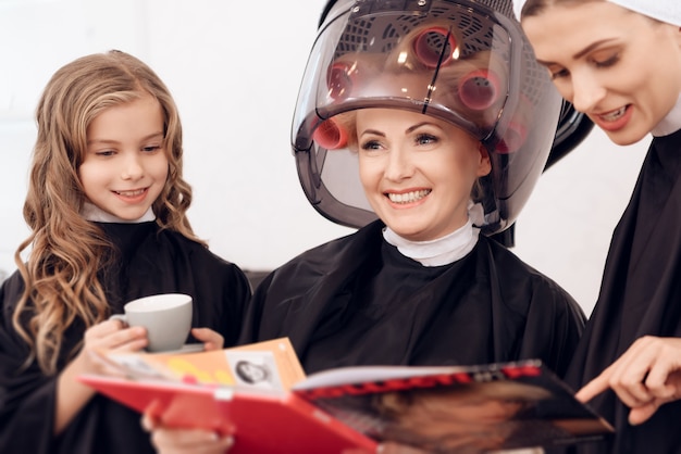 Femme avec des bigoudis sèche les cheveux avec sa fille.