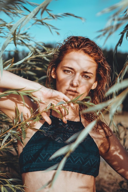 Femme en bikini sur une plage tropicale avec des plantes - heure d'été