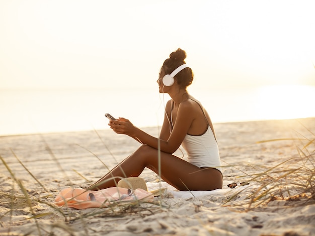 Femme en Bikini avec un smartphone et un casque sur la plage