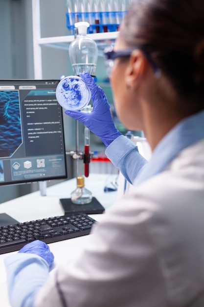 Femme biologiste regardant le virus bactérien à l'aide d'une boîte de Pétri médicale