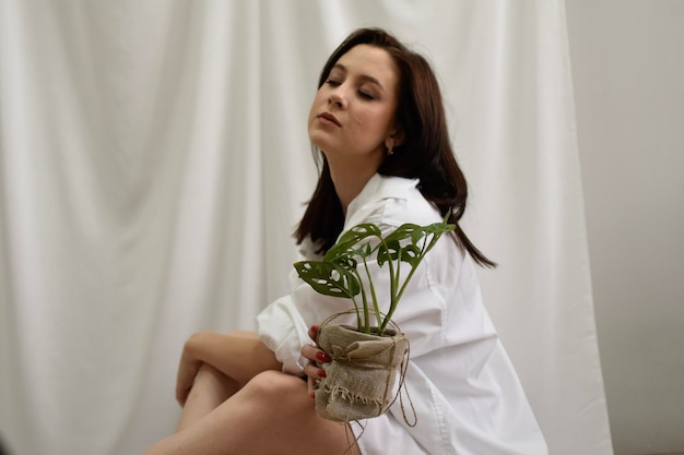 femme en blanc tenant un pot de fleurs à la maison