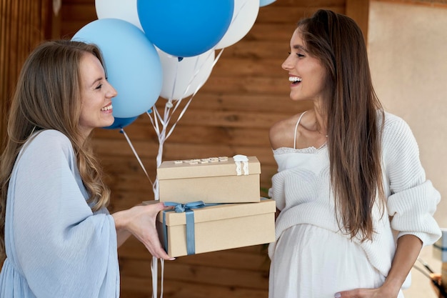 Une femme blanche donne des cadeaux à une amie enceinte.