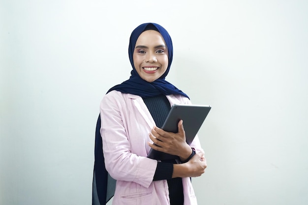 Une femme en blazer rose tient une tablette dans sa main.