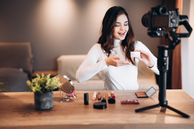 Femme blogueuse beauté filmant un tutoriel de routine de maquillage quotidien à la caméra. Influencer une jolie femme en direct, une revue de produits cosmétiques en streaming dans un home studio. Travail de blogueur.