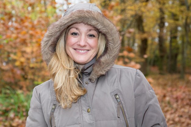 Femme blonde d'âge moyen souriante dans le parc d'automne