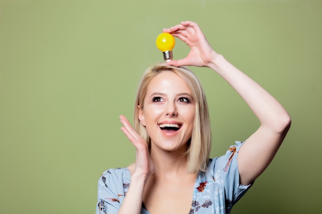 Femme blonde avec ampoule jaune sur mur vert