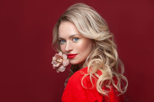 Une femme blonde attrayante avec une fleur sur un fond de bannière rouge