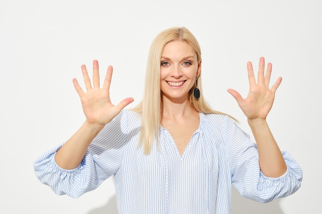 Une femme blonde attrayante montre dix doigts comptant avec les doigts