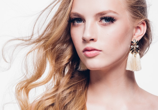 Femme blonde aux cheveux bouclés avec une longue belle coiffure et des cils de beauté isolés sur blanc. Prise de vue en studio.