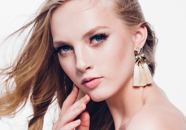 Femme blonde aux cheveux bouclés avec une longue belle coiffure et des cils de beauté isolés sur blanc. Prise de vue en studio.