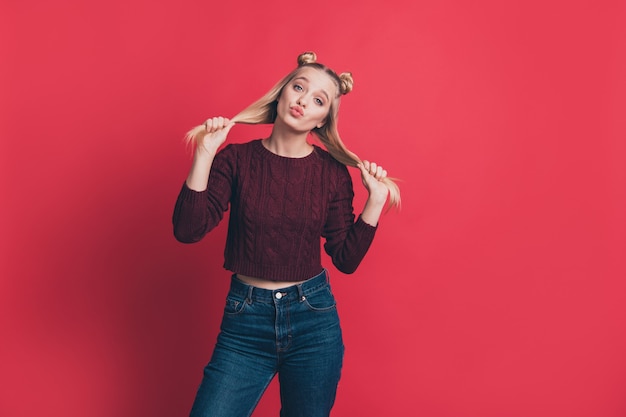 femme blonde aux noeuds supérieurs posant contre le mur rouge