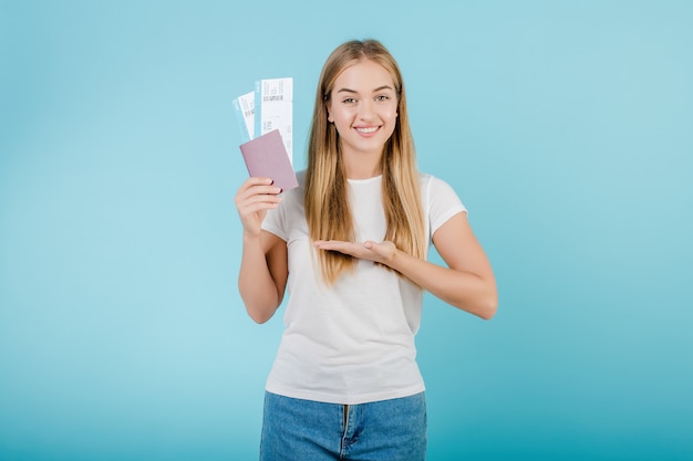 Femme blonde avec billets d'avion et passeport isolé sur bleu