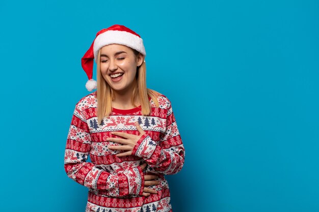 Femme blonde avec Bonnet de Noel rire aux éclats à une blague hilarante, se sentir heureux et joyeux, s'amuser