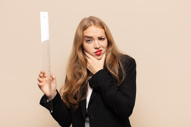 Femme blonde avec la bouche et les yeux grands ouverts et la main sur le menton, se sentant désagréablement choquée, disant quoi ou wow