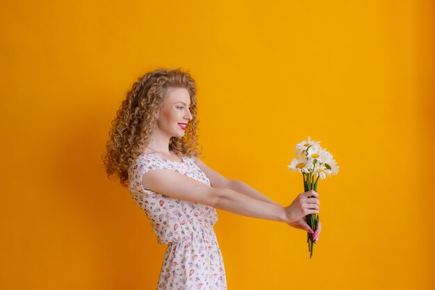 Photo une femme blonde bouclée tenant un bouquet de marguerites