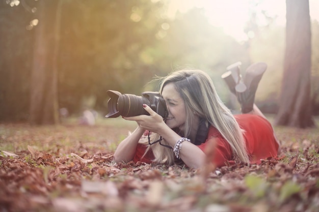 Femme blonde avec une caméra dans un parc