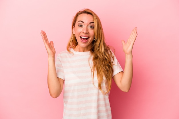 Femme blonde caucasienne isolée sur fond rose célébrant une victoire ou un succès, il est surpris et choqué.