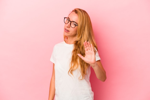 Femme blonde caucasienne isolée sur fond rose rejetant quelqu'un montrant un geste de dégoût.