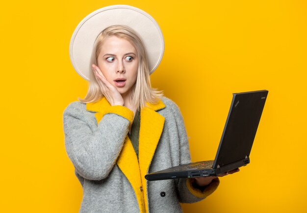 Femme blonde en chapeau et manteau avec ordinateur portable