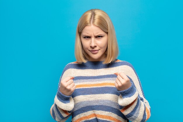 Femme blonde à la confiance, en colère, forte et agressive, avec les poings prêts à se battre en position de boxe