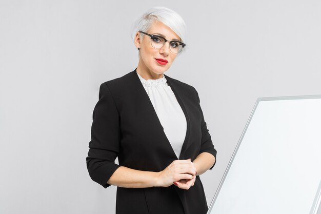 femme blonde en costume avec un tableau magnétique et smartphone