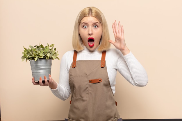 Femme blonde criant avec les mains en l'air, se sentant furieuse, frustrée, stressée et bouleversée