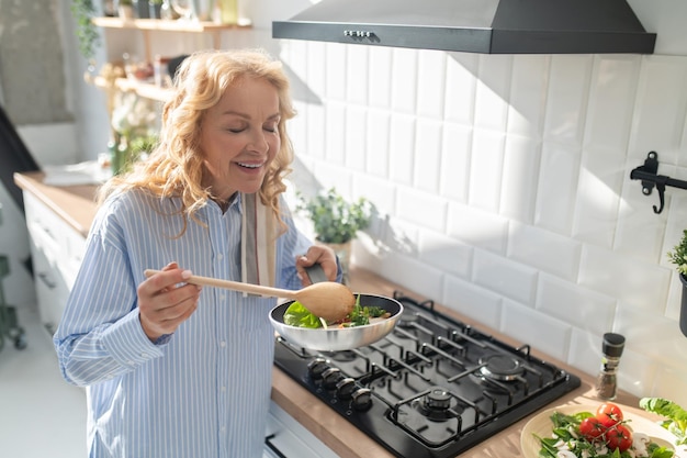 Femme blonde cuisinant et ayant l'air appréciée