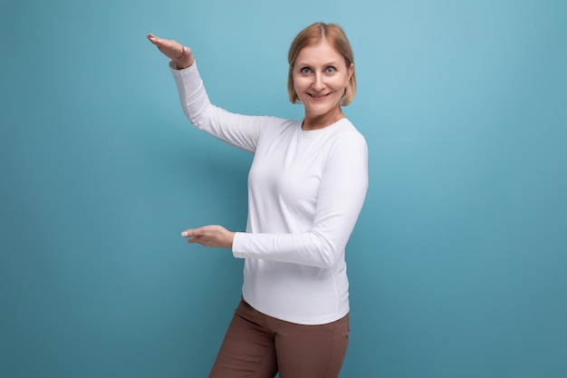 La femme blonde dans un chandail blanc démontre la taille avec ses mains