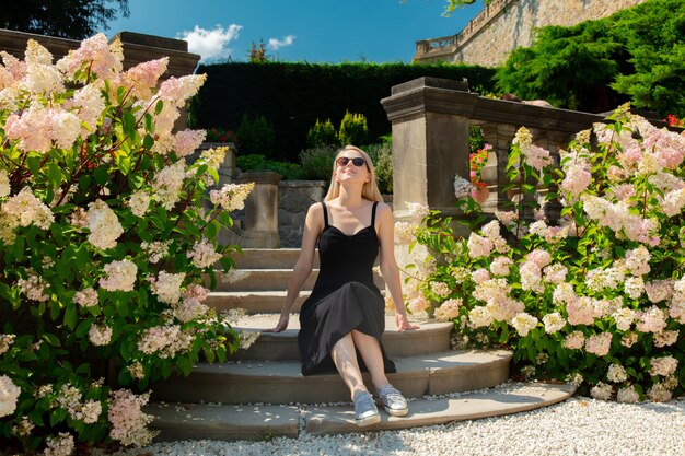 Femme blonde dans un jardin avec des fleurs d'hortensia