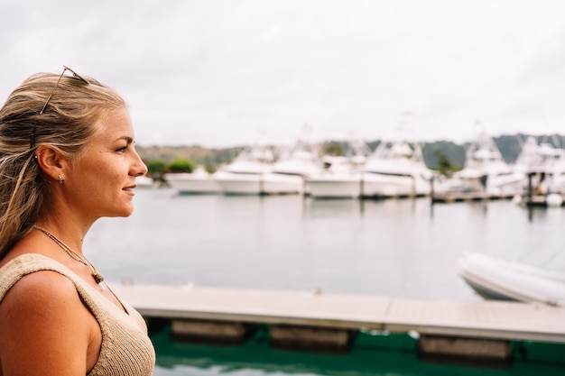 Femme blonde dans une jetée regardant des yachts amarrés