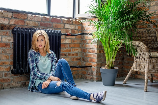 Femme blonde décontractée en jeans posant sur un sol dans le salon.