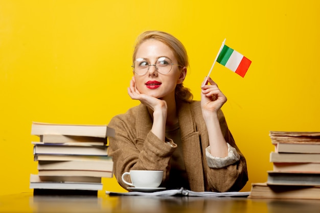 Femme blonde avec le drapeau de l'Italie et des livres sur jaune