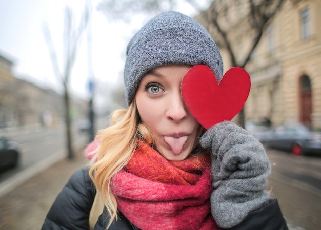 Femme blonde drôle avec un coeur de papier