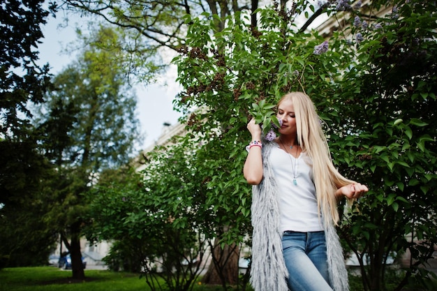 Femme blonde élégante porter des jeans et une fille sans manches avec une chemise blanche contre lilas Portrait de modèle urbain de mode