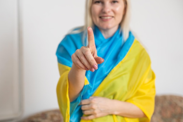 Femme blonde enveloppée dans le drapeau de l'Ukraine. Prise en charge du concept ukrainien