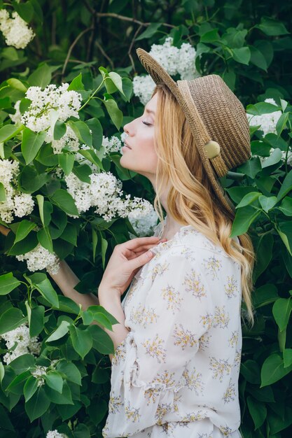 Femme blonde avec des fleurs lilas au printemps