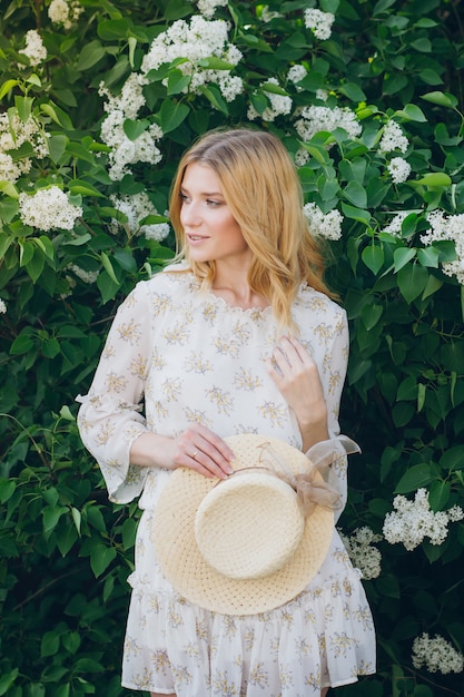 Femme blonde avec des fleurs lilas au printemps