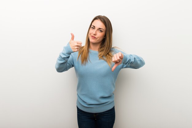 Femme blonde sur fond blanc isolé fait bon signe. Indécis entre oui ou non