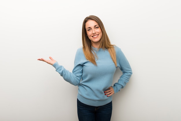 Femme blonde sur fond blanc isolé tenant une surface imaginaire sur la paume pour insérer une annonce