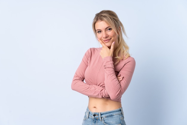 Femme blonde sur fond bleu isolé heureux et souriant