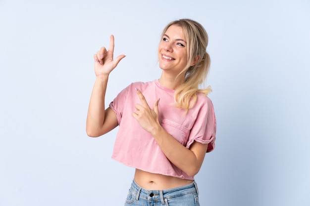 Femme blonde sur fond bleu isolé pointant avec l'index une excellente idée