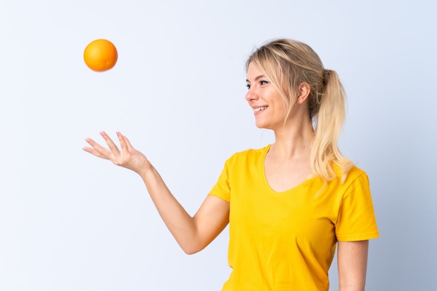 Femme blonde sur fond bleu isolé tenant une orange