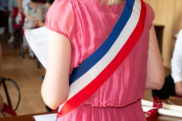 Photo femme blonde française maire avec écharpe france drapeau tricolore et fille robe rose lors de la célébration officielle à l'hôtel de ville france