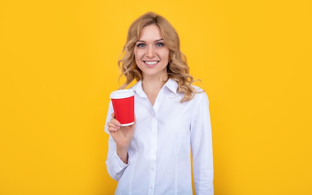 Femme blonde gaie avec une tasse de café sur fond jaune