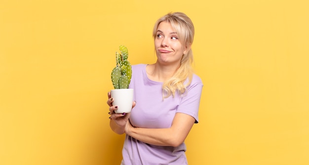 Femme blonde haussant les épaules, se sentant confus et incertain, doutant des bras croisés et regard perplexe